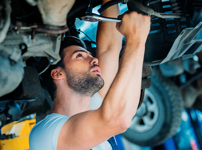 car maintenance Automechanic working on a lifted up car in a repair workshop