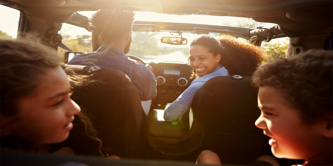 young family driving in car with kids