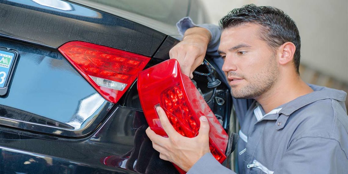 Man replacing tail light in auto shop