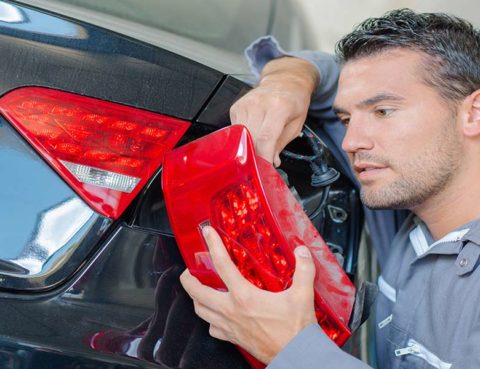 Man replacing tail light in auto shop