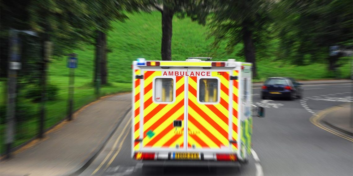 Ambulance driving around a curve with cars nearby.