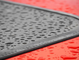 Roof of red car with sunroof covered in water droplets